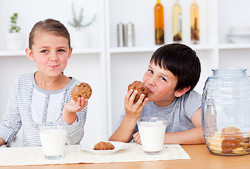 Two children eating cookies and milk